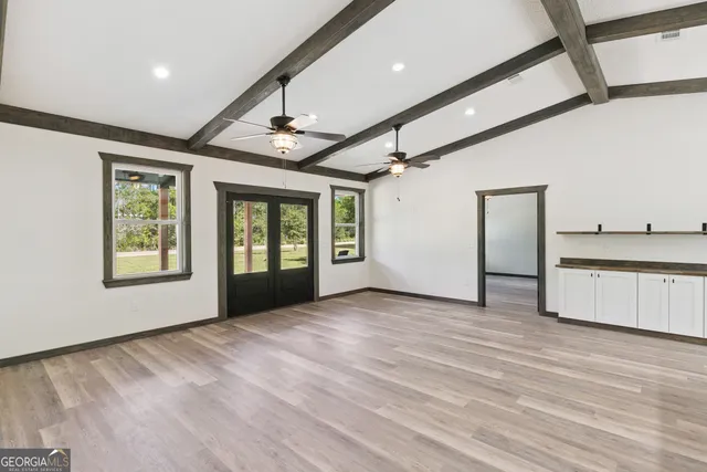 a view of an empty room with a window and wooden floor