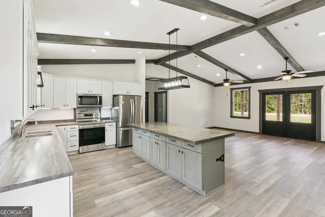 a large kitchen with cabinets wooden floor and stainless steel appliances