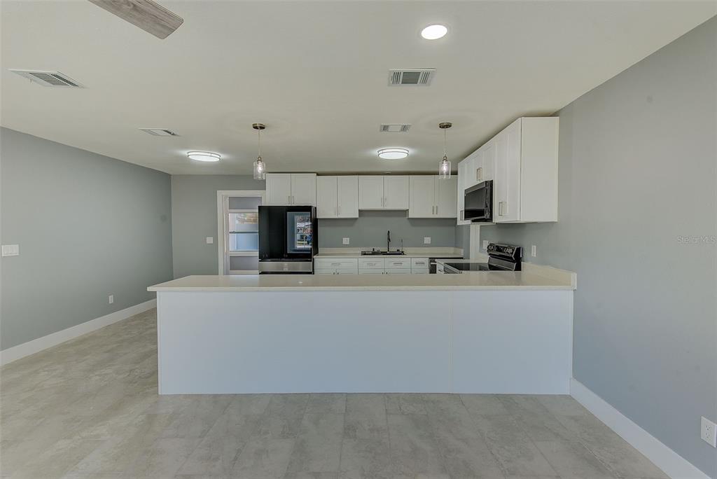6208 Florida Circle East Apollo Beach, FL 33572 - Photo 8 of 43 a living room with stainless steel appliances a kitchen island a sink a stove a microwave a refrigerator a stove with white cabinets