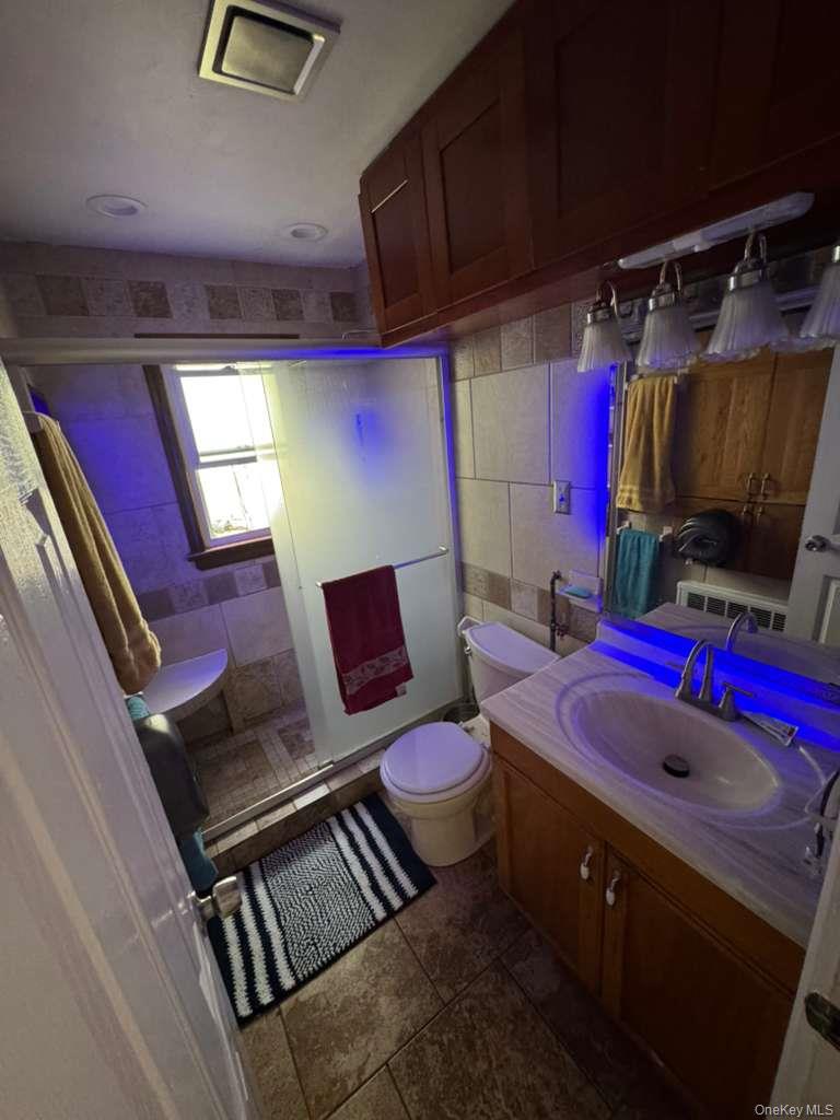 35 Harvard Street Valley Stream, NY 11580 - Photo 8 of 19 Full bath with tile walls, a stall shower, vanity, and dark tile patterned floors