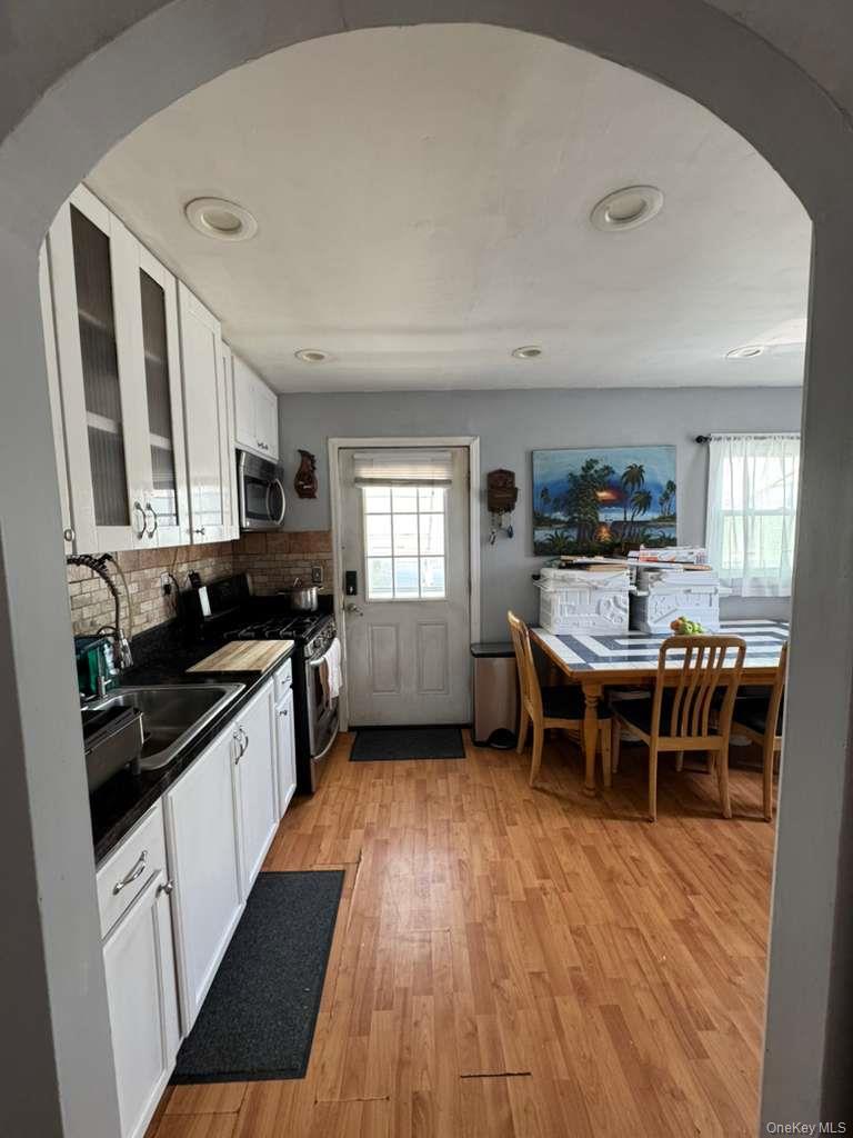 35 Harvard Street Valley Stream, NY 11580 - Photo 10 of 19 Kitchen with white cabinetry, arched walkways, dark countertops, glass insert cabinets, and stainless steel appliances