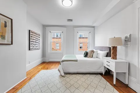 a bedroom with a bed and a lamp on dresser