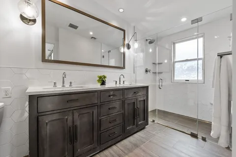 a spacious bathroom with a double vanity sink a mirror and a shower