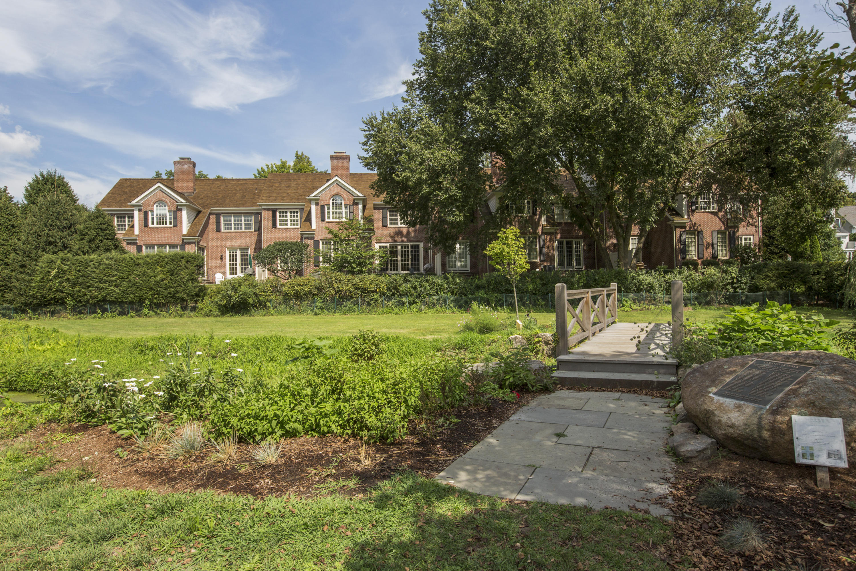 30 Richmond Hill Road, Unit 4 New Canaan, CT 06840 - Photo 35 of 40 a view of a garden with a bench in front of the house
