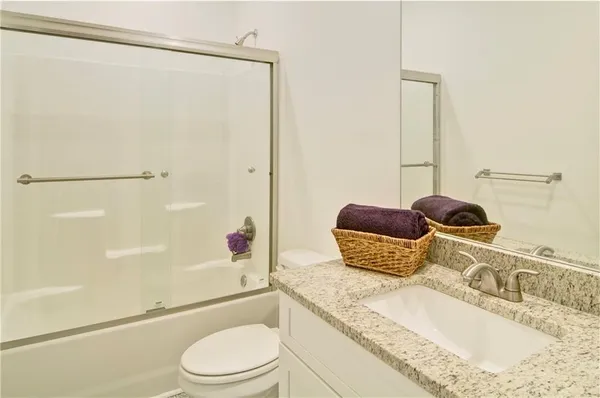 a bathroom with a granite countertop sink toilet and shower