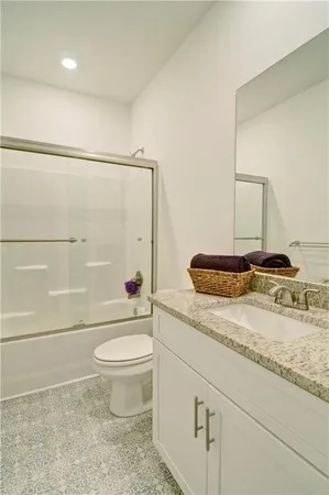 a bathroom with a granite countertop sink toilet and a mirror