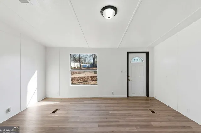 a view of an empty room with wooden floor and a window