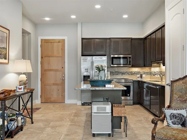 a kitchen with kitchen island granite countertop wooden cabinets and a refrigerator