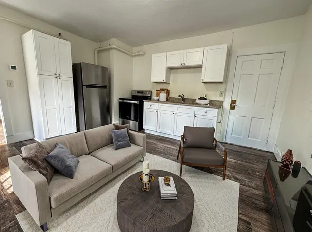 a living room with furniture and a refrigerator