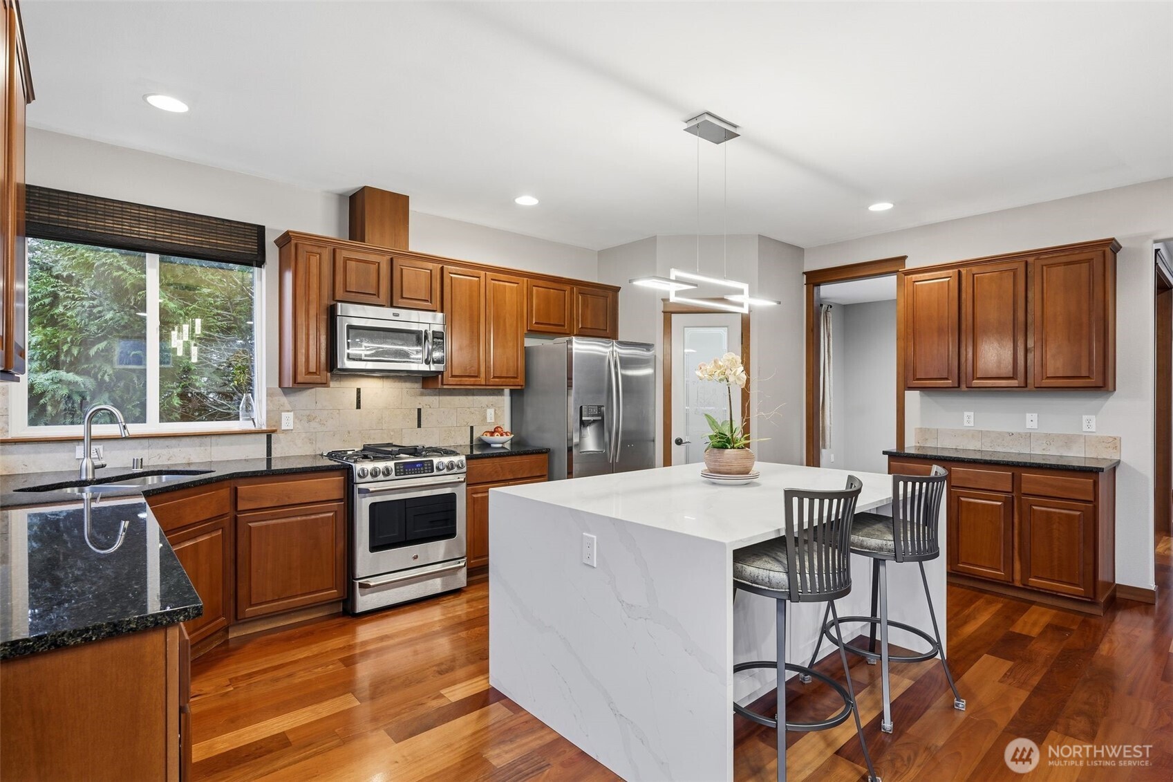 18408 41st Drive Southeast Bothell, WA 98012 - Photo 8 of 25 a kitchen with stainless steel appliances granite countertop a stove top oven a sink dishwasher a dining table and chairs with wooden floor