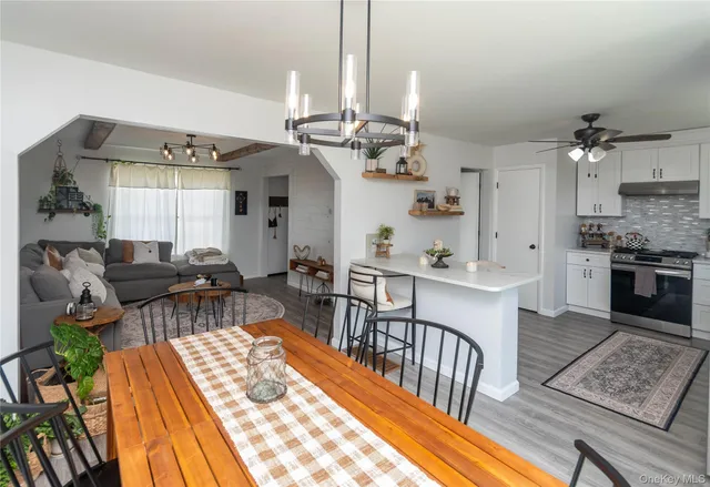 a view of a dining room and livingroom with furniture wooden floor a chandelier