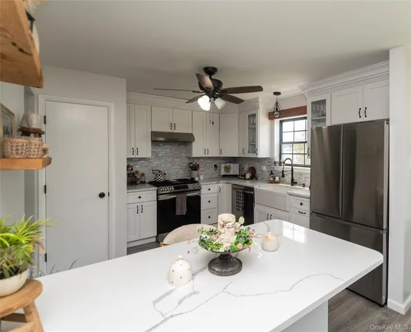 a kitchen with a refrigerator a stove a sink and white cabinets with wooden floor