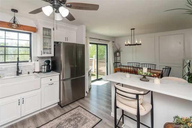 a kitchen with a refrigerator a sink dishwasher a dining table and chairs with wooden floor