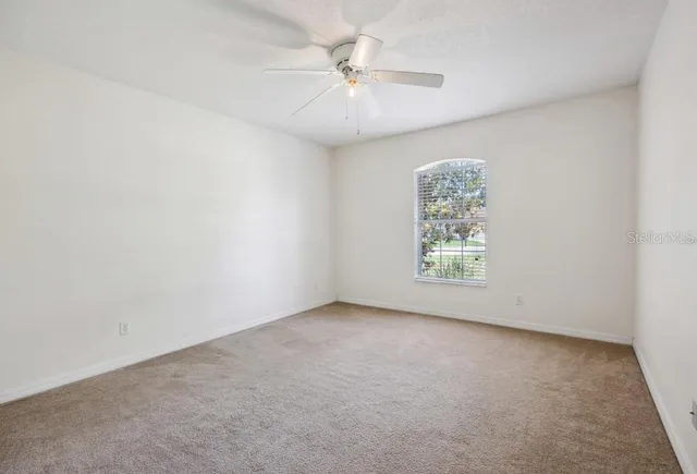 an empty room with windows and fan