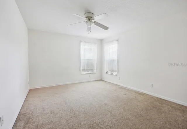 an empty room with a ceiling fan and a window