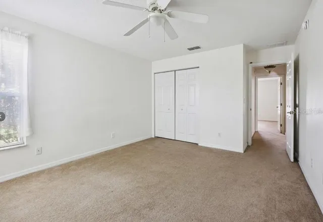 a view of an empty room and chandelier fan