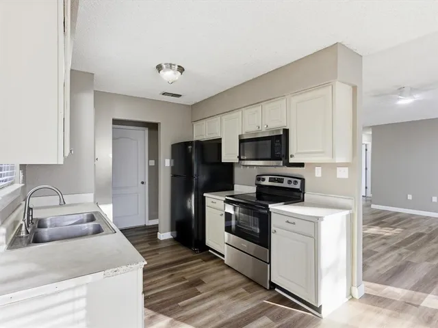a kitchen with granite countertop a sink stainless steel appliances and cabinets