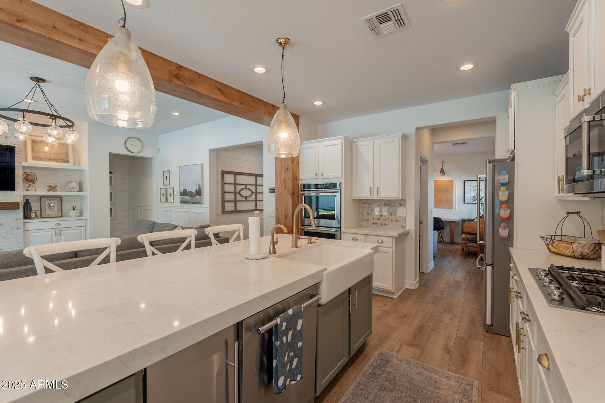 3931 East Weather Vane Road Gilbert, AZ 85296 - Photo 28 of 83 a large kitchen with stainless steel appliances a stove a sink dishwasher and a dining table with white cabinets