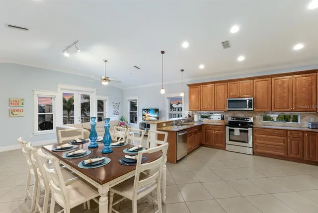 a kitchen with stainless steel appliances granite countertop a stove top oven a sink dishwasher a dining table and chairs with wooden floor