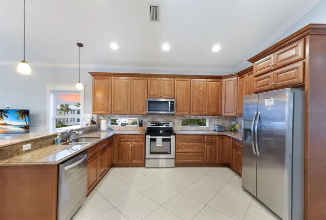 a kitchen with stainless steel appliances granite countertop a refrigerator a sink a stove a microwave and island