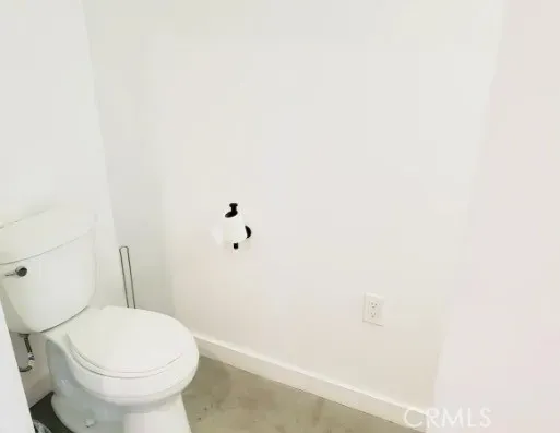 a white toilet sitting next to a white wall