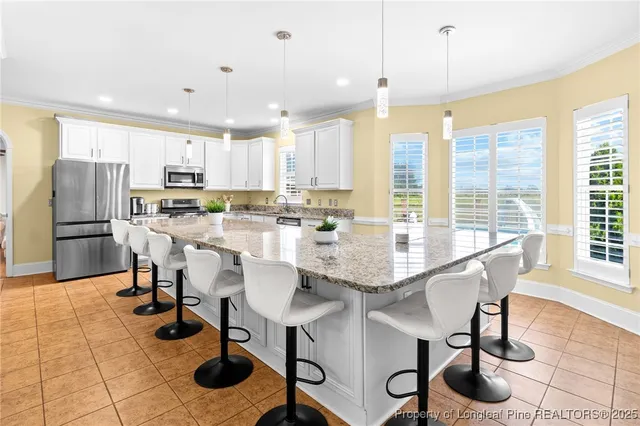 a kitchen with stainless steel appliances granite countertop a table chairs and a refrigerator