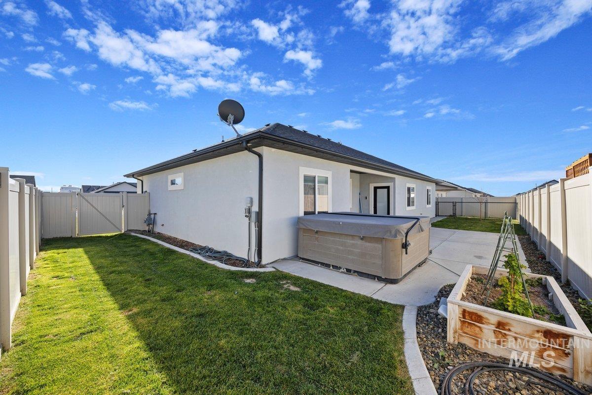924 Trapper Peak Road Kimberly, ID 83341 - Photo 36 of 40 Back of house featuring a fenced backyard, a patio area, stucco siding, a gate, and a vegetable garden