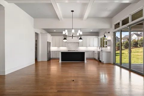 a view of an empty room with wooden floor fireplace and a window