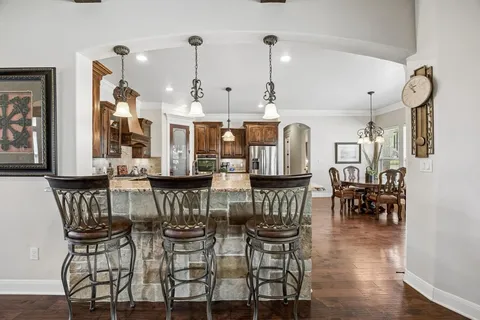 a kitchen with stainless steel appliances granite countertop a table chairs stove and refrigerator