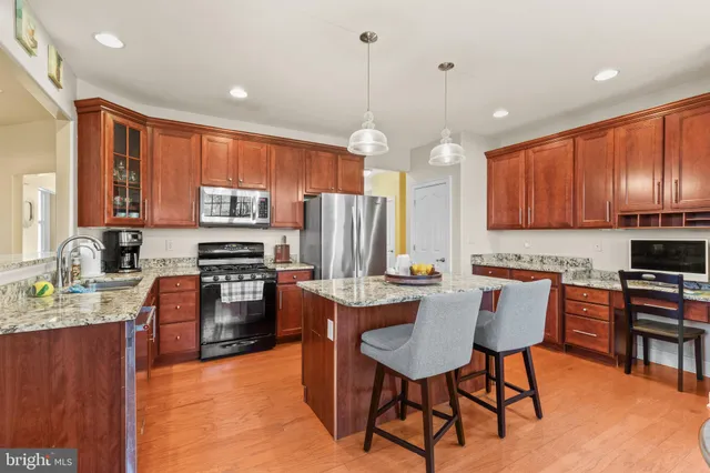 a kitchen with stainless steel appliances granite countertop a stove top oven a sink dishwasher a dining table and chairs with wooden floor