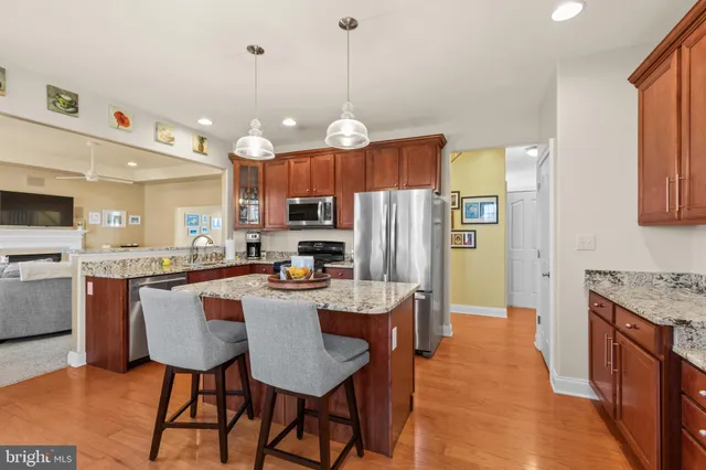 a kitchen with stainless steel appliances kitchen island granite countertop a table chairs and a refrigerator