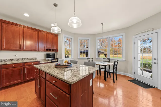 a open kitchen with stainless steel appliances granite countertop a stove top oven a dining table and chairs with wooden floor