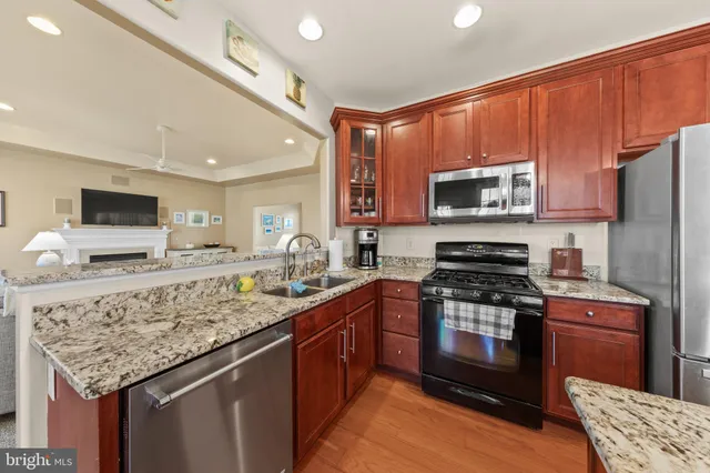 a kitchen with stainless steel appliances granite countertop a stove top oven a sink dishwasher a refrigerator and a microwave