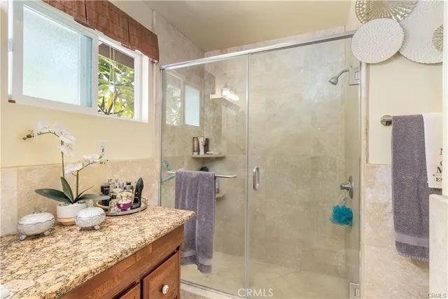 a bathroom with a granite countertop sink a mirror and a shower