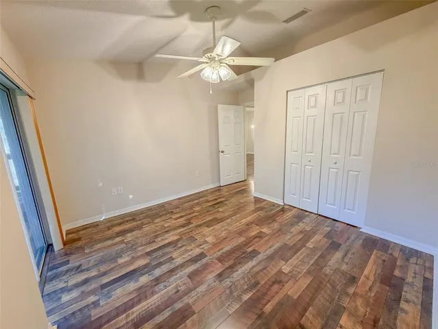 a view of a room with wooden floor and fan in a room