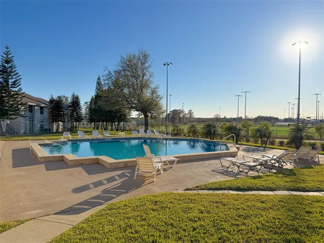 a view of swimming pool with trees and house in the background