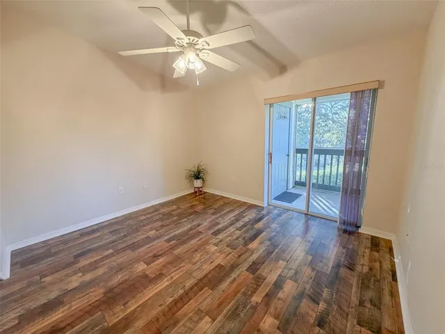 an empty room with wooden floor fan and windows