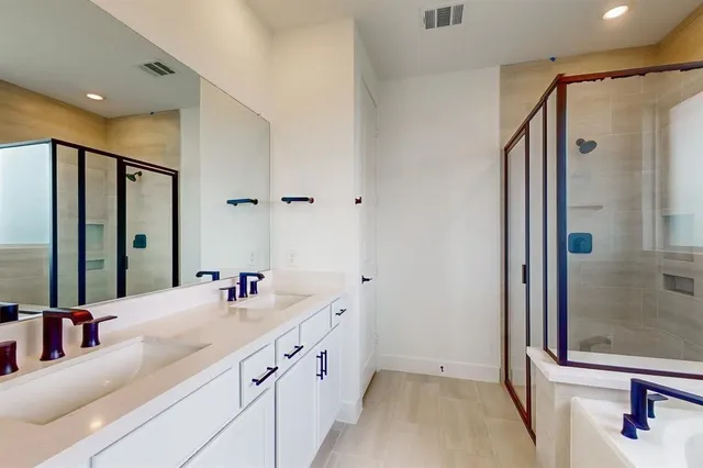 a bathroom with a double vanity sink mirror and shower
