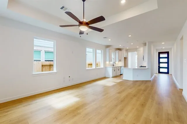 a view of an empty room with a window and wooden floor