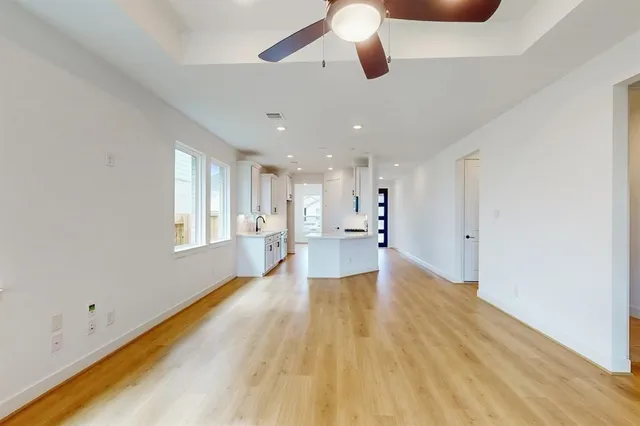 a view of a big room with wooden floor a ceiling fan and windows