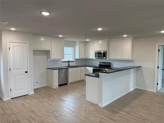 a kitchen with granite countertop a sink cabinets and wooden floor