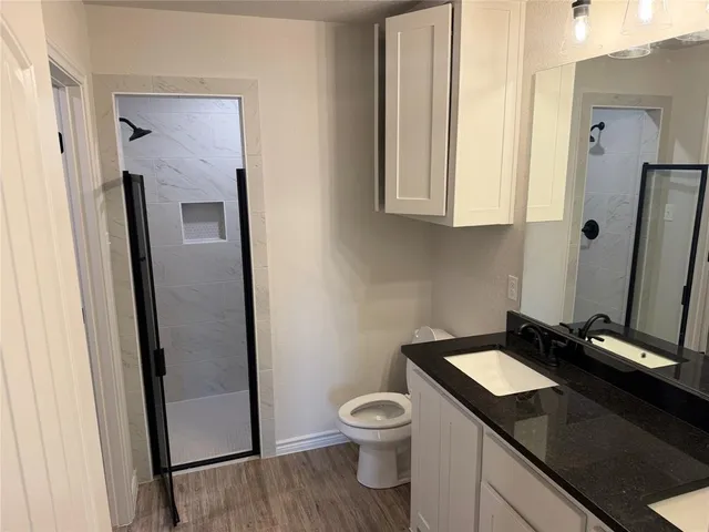 a bathroom with a granite countertop sink toilet and mirror