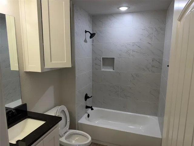 a bathroom with a granite countertop sink toilet and bathtub