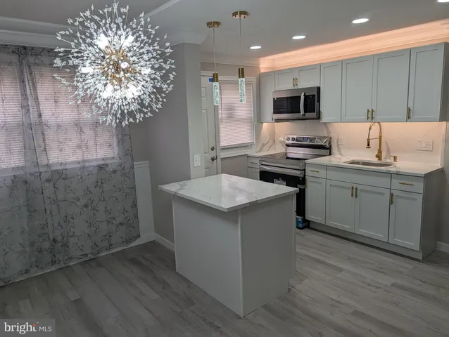 a kitchen with a sink a microwave a stove and cabinets