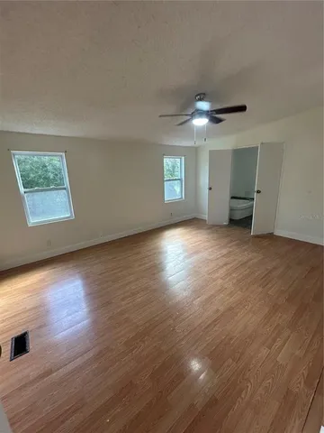 an empty room with wooden floor chandelier and windows
