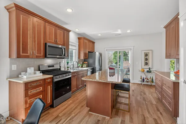 a kitchen with kitchen island a stove a sink a refrigerator cabinets and wooden floor