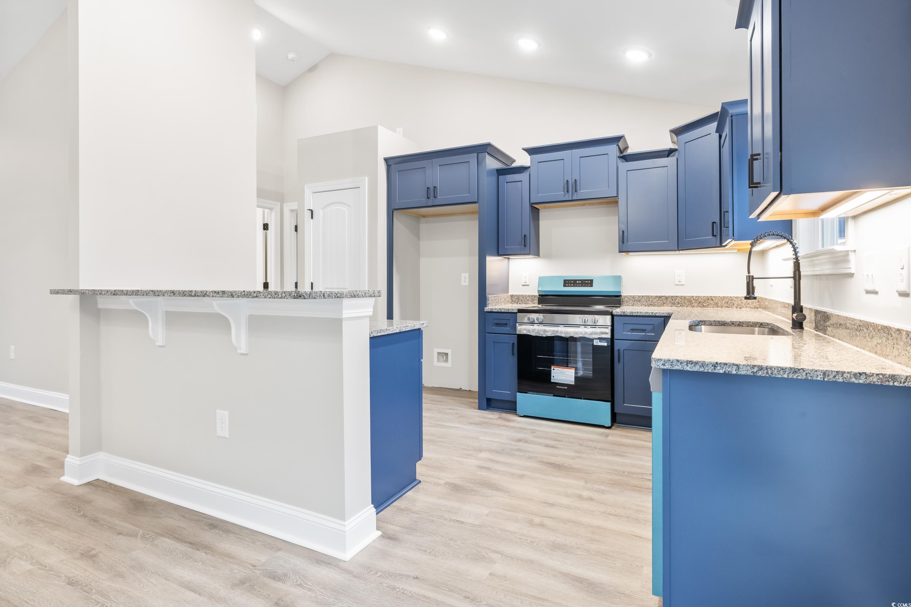 3646 Bethel Chapel Road Loris, SC 29569 - Photo 20 of 40 Kitchen with light stone countertops, stainless steel electric stove, a kitchen bar, lofted ceiling, and light wood-style floors