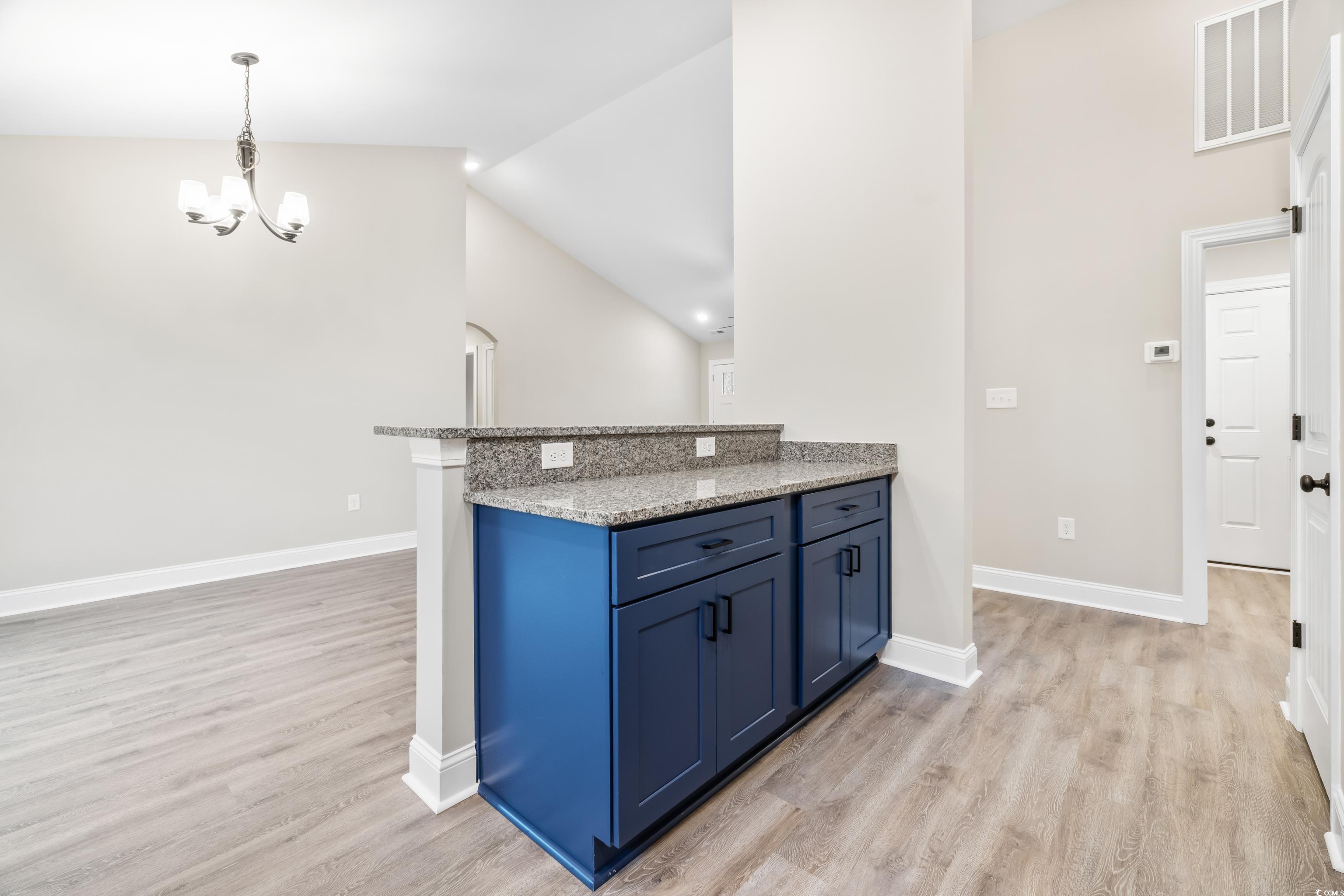 3646 Bethel Chapel Road Loris, SC 29569 - Photo 23 of 40 Kitchen featuring dark stone counters, blue cabinetry, pendant lighting, light wood finished floors, and vaulted ceiling
