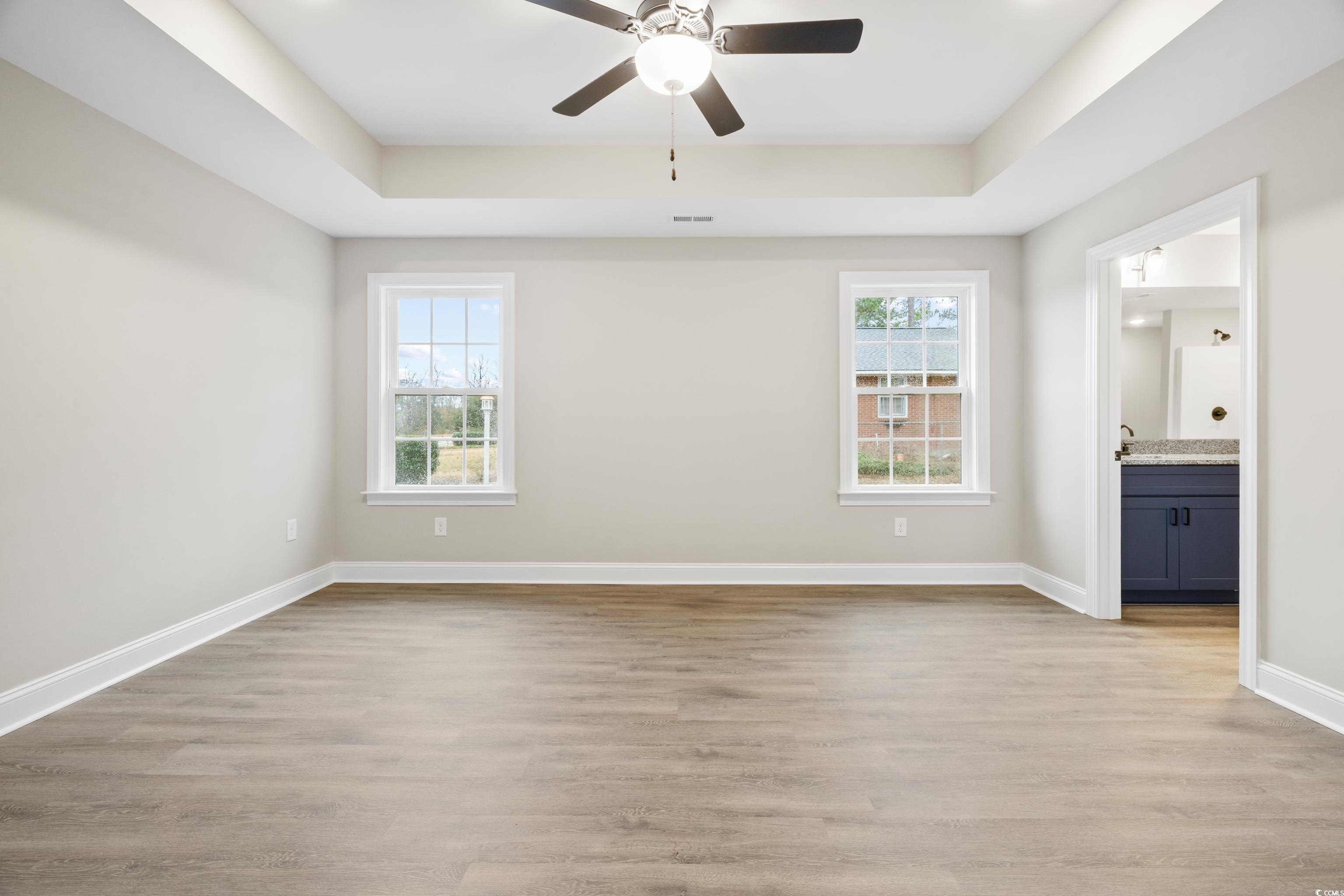 3646 Bethel Chapel Road Loris, SC 29569 - Photo 25 of 40 Unfurnished bedroom featuring light wood finished floors, a tray ceiling, connected bathroom, and ceiling fan