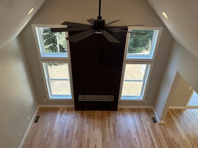 an empty room with wooden floor windows and ceiling fan